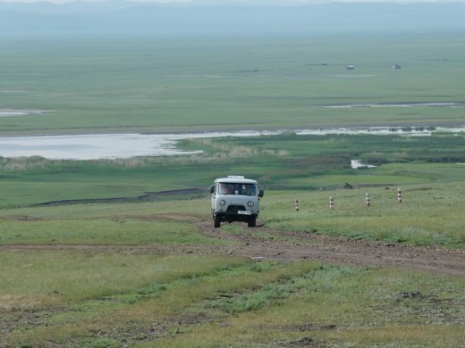 A UAZ furgon van on a dirt track across green steppe in Khentii province